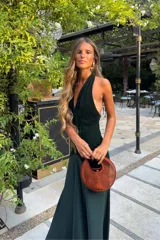 Vestido largo verde oscuro de terciopelo y satén, con escote halter pronunciado y diseño ajustado en el torso con caída fluida en la falda.