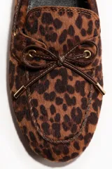Mocasines tipo náuticos con estampa animal print de leopardo, con detalle de cordones decorativos marrones en el empeine y ojales metálicos dorados.
