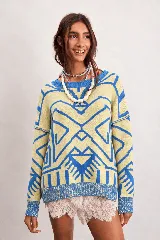 Buzo oversize de punto color marfil con diseño geométrico jacquard en tonos rosado, amarillo, celeste y marrón. Cuenta con cuello redondo y mangas largas.