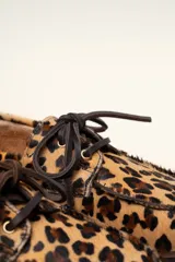 Mocasín tipo boat shoe color marrón, confeccionado en cuero, con cordones de cuero marrón y cordones decorativos azules.