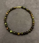 Collar de cuentas de piedras naturales en tonos verdes, marrones y negros con cierre metálico dorado.