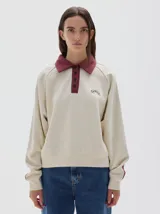 Buzo de friza suave color azul marino, con cuello polo y cartera de botones en contraste azul denim. Mangas raglán con franjas laterales azules y logo bordado en el pecho.