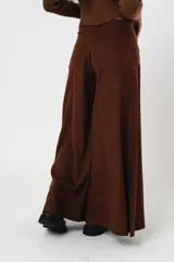 Pantalón marrón acampanado de tiro medio, con bolsillos delanteros y traseros. Cierre frontal con cremallera y botón.