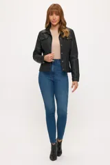 Campera de cuero sintético en color negro, con diseño tipo trucker, cuello clásico, cierre frontal con botones metálicos y bolsillos con solapa en el pecho.
