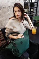 Bolso tipo tote negro de tela impermeable, con doble asa de mano y cierre superior con cremallera. Incluye un colgante decorativo de cordón blanco y negro.