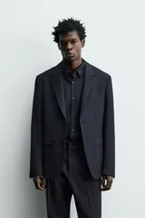 Blazer de corte regular confeccionado en tejido de lana italiana. Presenta cuello con solapas de muesca, cierre frontal de un botón, bolsillos laterales con solapa y bolsillo de vivo en el pecho. Incluye aberturas en la espalda y forro interior.