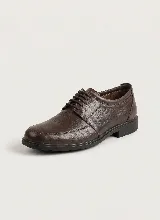 Zapato de vestir tipo derby, confeccionado en cuero legítimo color marrón oscuro, con cordones al tono, costuras reforzadas y suela de goma negra.