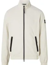 Campera Calvin Klein color beige claro, confeccionada en nailon arrugado reciclado. Tiene cuello alto, puños y bajo elásticos, cierre con cremallera, bolsillos con cremallera en la cintura, abertura de ventilación en la espalda, forro de poliéster reciclado e insignia con el logo de goma de Calvin Klein en la manga.