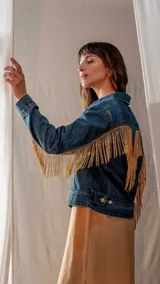 Campera de jean azul con flecos de strass dorados en mangas y espalda.