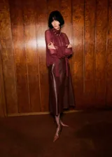 Blusa de viscosa color bordó, con diseño semitransparente, cuello drapeado con adorno de fular y mangas largas con puños elásticos.