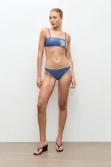 Top de bikini bandeau color azul con detalle de bordado floral en hilo crudo en el lateral.