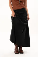 Pollera larga de color negro con corte a la cadera y detalle de frunce que aporta volumen y movimiento a la prenda. Confeccionada en tela suave con acabado tipo piel de durazno.