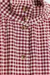 Chaqueta de manga larga con estampado de cuadros vichy en tonos marrón y blanco, cuello camisero, cierre frontal con botones y bajo ajustable con cordón.