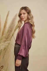 Blusa de satén color champagne con cuello a la base, mangas anchas y puños elásticos con detalle bordado.