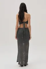 Vestido tejido calado plateado, con escote halter, cut outs en el abdomen y falda larga con tajo lateral.