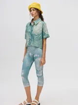 Camisa corta celeste con estampado de nubes, cuello clásico, manga corta y cierre frontal con botones.