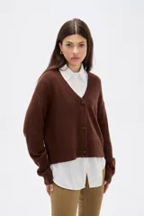 Cardigan de punto color marrón, con cuello en V profundo, cierre frontal con botones y diseño holgado de manga larga.