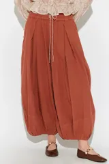 Pantalón balloon de tela liviana y fluida, color rojo terracota, con cintura elastizada, cordón de ajuste, pinzas frontales y diseño abullonado en los tobillos.