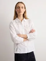 Camisa amarilla de manga larga con detalles bordados y calados en los hombros, pecho y mangas, corte clásico con cuello camisero y cierre frontal de botones.