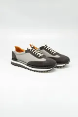 Championes de cuero italiano combinados en gris y negro, con cordones elásticos y cordones de algodón de repuesto. Suela de goma blanca con dibujo.