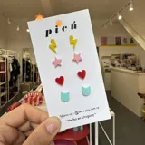 Pack de cuatro pares de aros pequeños con forma de rayo amarillo, estrella rosa, corazón rojo y gato celeste.