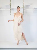 Vestido largo color crema, con escote en V y tirantes finos con detalle de nudos. Presenta tajos laterales en el ruedo.
