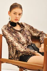 Camisa de manga larga con cuello camisero y corte masculino, confeccionada en poliéster con estampado de piel de serpiente en tonos marrones y beige.