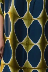 Kaftan maxi amplio de color amarillo, con escote redondo, mangas cortas y ruedo irregular. Presenta un diseño estampado a cuadros con efecto teñido.