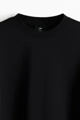Buzo de mezcla de algodón en color negro, con cuello redondo, hombros caídos y puños y bajo acanalados.