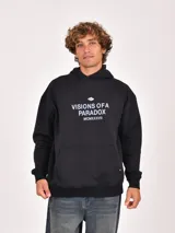 Buzo canguro negro con capucha, manga larga y bolsillo canguro frontal. Presenta un estampado blanco en el pecho con un logo circular y el texto "VISIONS OF A PARADOX MCMXXXVII".
