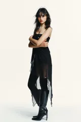 Top strapless negro con diseño asimétrico, confeccionado con una capa superior de tela opaca y una capa inferior de tejido semitransparente con caída irregular.