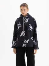 Buzo con capucha de corte holgado, confeccionado en tela de punto color negro con estampado integral de corazones atravesados por flechas en tonos grises y blancos. Presenta cordones ajustables en la capucha y mangas largas.