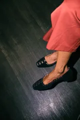 Mocasines de gamuza negra con detalle de costuras cruzadas en tono bronce a lo largo del borde y en la puntera. Poseen un taco bajo cuadrado de 2 cm.