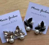 Par de caravanas con forma de racimo, con perlas blancas, piedras negras en forma de hoja y strass plateado. Cierre a presión.