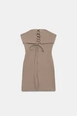 Vestido mini taupe de escote palabra de honor y hombros descubiertos, con detalle de tejido superpuesto y tiras cruzadas ajustables en el pecho. Cuenta con cierre lateral con cremallera oculta.