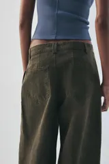 Pantalón verde militar de tiro medio, con bolsillos delanteros, pliegues y tejido con efecto lavado. Cuenta con cierre frontal con cremallera y gancho metálico.