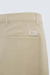 Pantalón chino de corte ajustado, color beige, con bolsillos laterales y bolsillos traseros de vivo. Cuenta con cierre frontal de cremallera y botón.