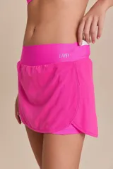 Pollera deportiva color rosa fucsia, con estampado en relieve de texto. Es de corte corto con ruedo redondeado y cuenta con shorts internos.