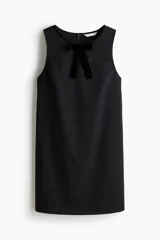 Vestido corto sin mangas color negro con silueta evasé, escote bote y detalle de moño de terciopelo en el frente.