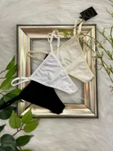 Pack de tres tangas de algodón con tiras laterales regulables. El conjunto incluye una prenda negra, una blanca y una color champagne.