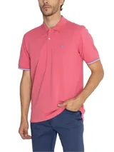 Chomba de piqué color rosa con cuello clásico y tapeta de dos botones. Tiene mangas cortas con puños acanalados con detalles de líneas blancas y azules. Presenta un logo bordado en el pecho.