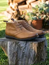 Botín tipo chukka de cuero color suela, con cordones al tono, costuras reforzadas y suela de goma negra.
