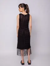 Vestido largo negro de tejido de punto con diseño de tramado y pequeños calados, sin mangas y con flecos en el ruedo.