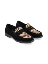 Mocasín de gamuza negra con detalle de cuero con estampado animal print tipo cebra en el empeine y banda frontal característica.
