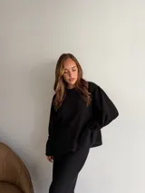 Buzo de textura acanalada en color negro, con cuello redondo y mangas largas con puños ajustados. Presenta un corte holgado y diseño minimalista.