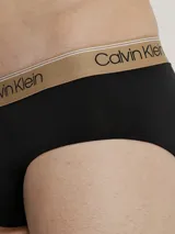 Pack de 3 slips Calvin Klein de corte clásico, confeccionados en tejido micro stretch de poliéster y elastano. Incluye tres slips negros con cinturas elásticas de diferentes colores: gris, dorado y blanco, con el logo de la marca.