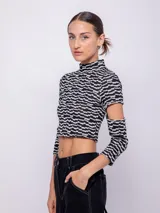 Top corto de tejido con estampado geométrico retro en tonos rosa, gris y negro. Es de manga larga con cut-out en los codos y cuello alto.