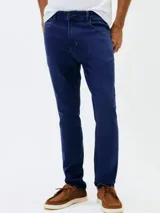 Pantalón de jean corte skinny, color azul medio, con diseño de cinco bolsillos y cierre frontal con botón y cremallera.