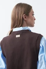 Chaleco tejido de punto color marrón oscuro, con botones frontales y diseño de punto calado vertical.