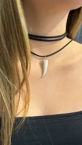 Choker doble de gamuza negra con un dije colgante en forma de colmillo de metal plateado.